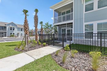 A modern building with a black fence and a small garden in front at The Junction at Rockledge Apartments, Florida